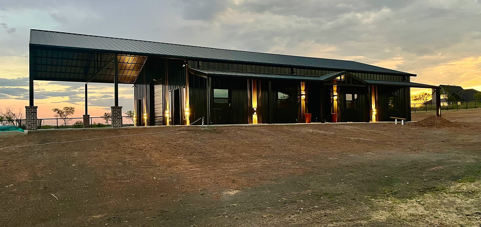 Modern barn with metal roof and siding at sunset.