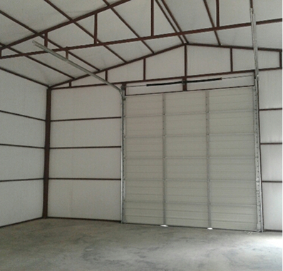Empty white metal building with large garage door.
