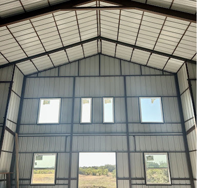 Interior of a metal building with a gable roof and windows.